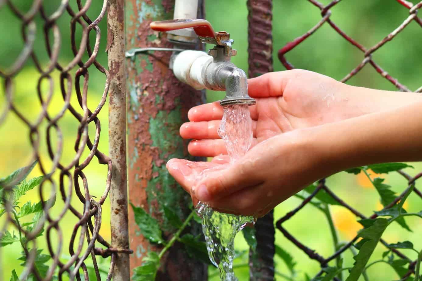 Close up child hands with water garden tap